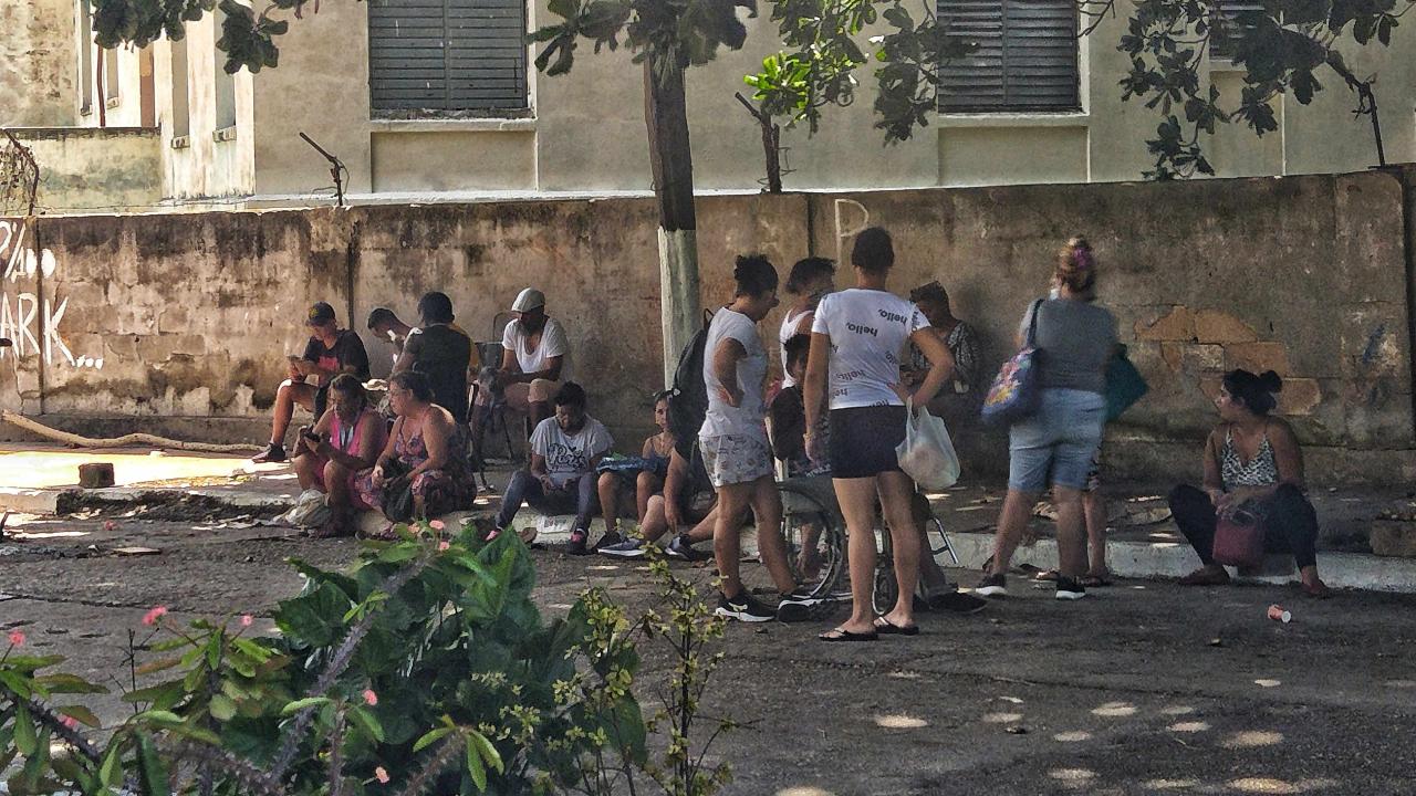 Cubanos revisando internet mientras esperan en una cola.