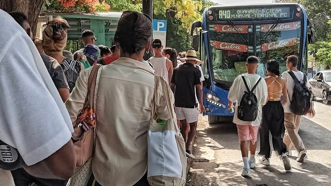 Cubanos hacienco cola para subir a una guagua en La Habana.